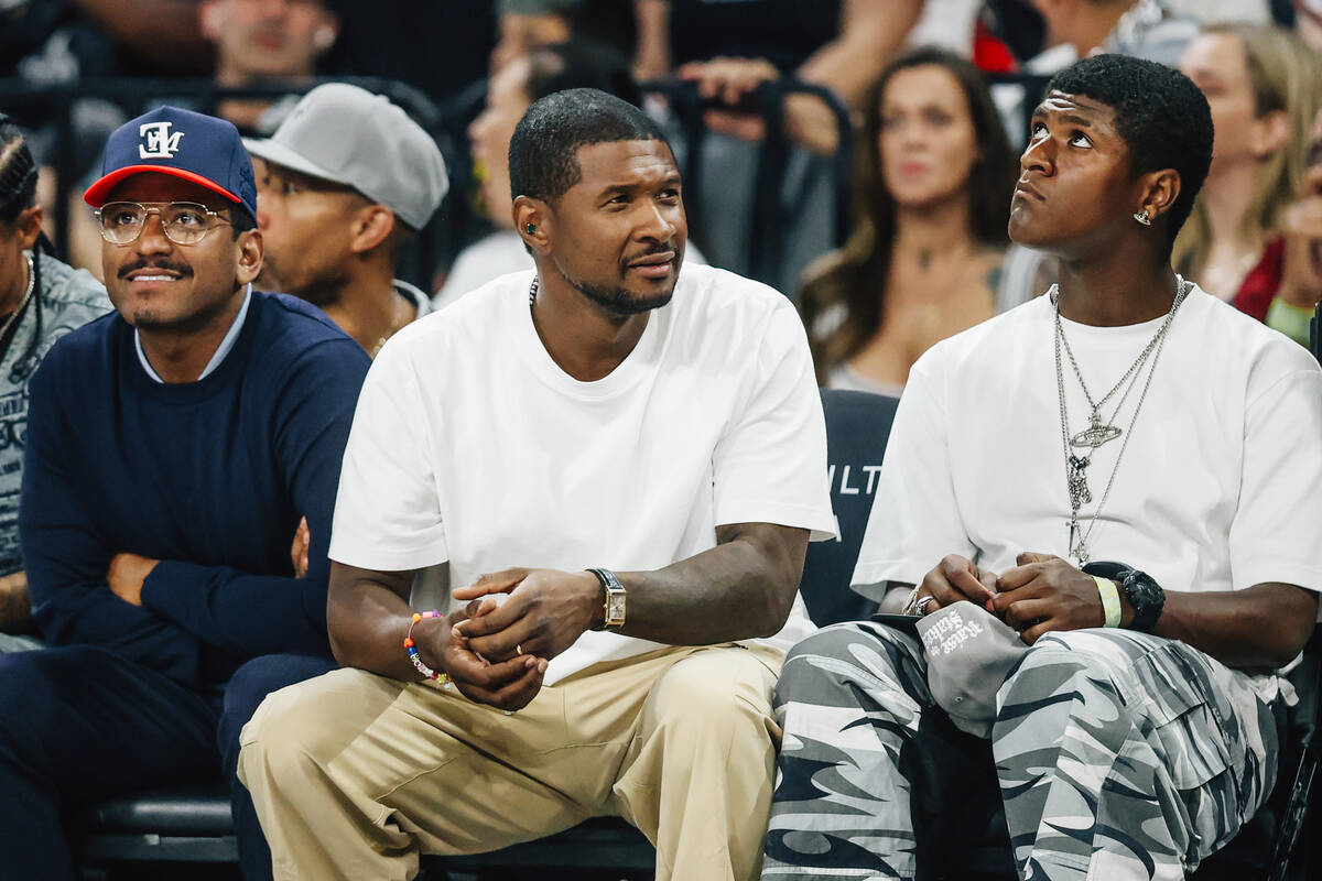 Usher, middle, sits on the sidelines with singer Lloyd, left, during game two of of a WNBA fina ...