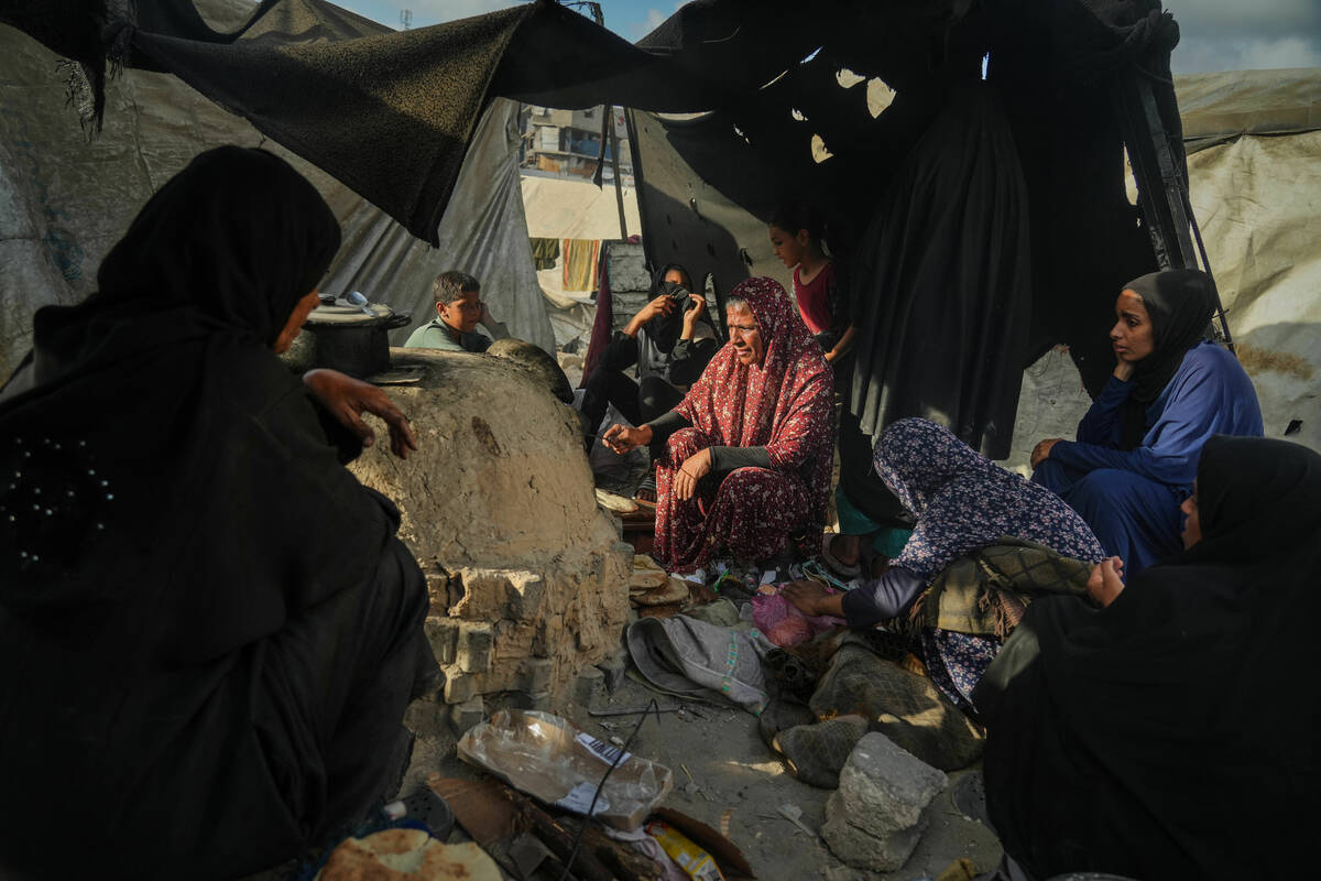 Palestinian women bake bread in a clay oven, using plastic for fire, at a UN school used as a s ...