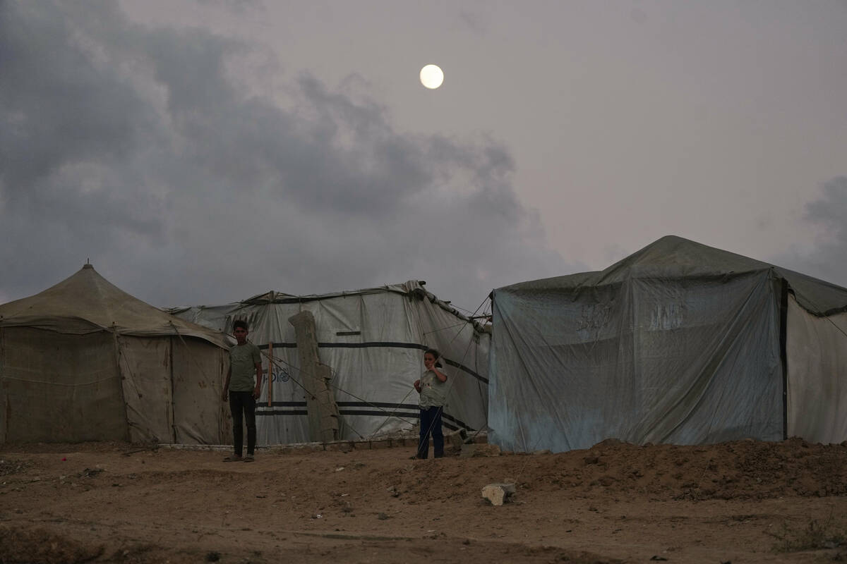 Displaced Palestinians kids stand by a makeshift tent camp along the shore of Nuseirat, central ...