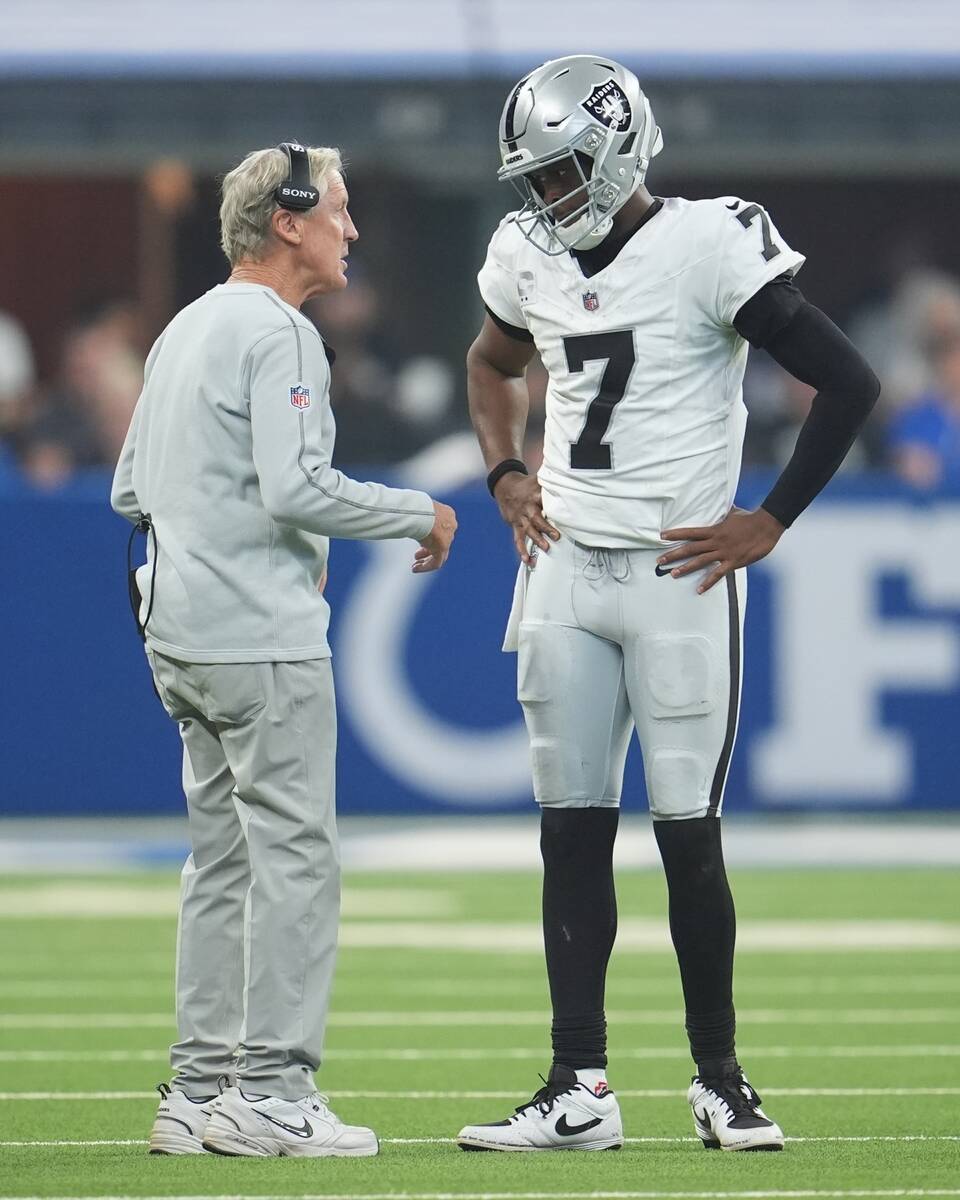 Las Vegas Raiders head coach Pete Carroll talks with quarterback Geno Smith during the first ha ...