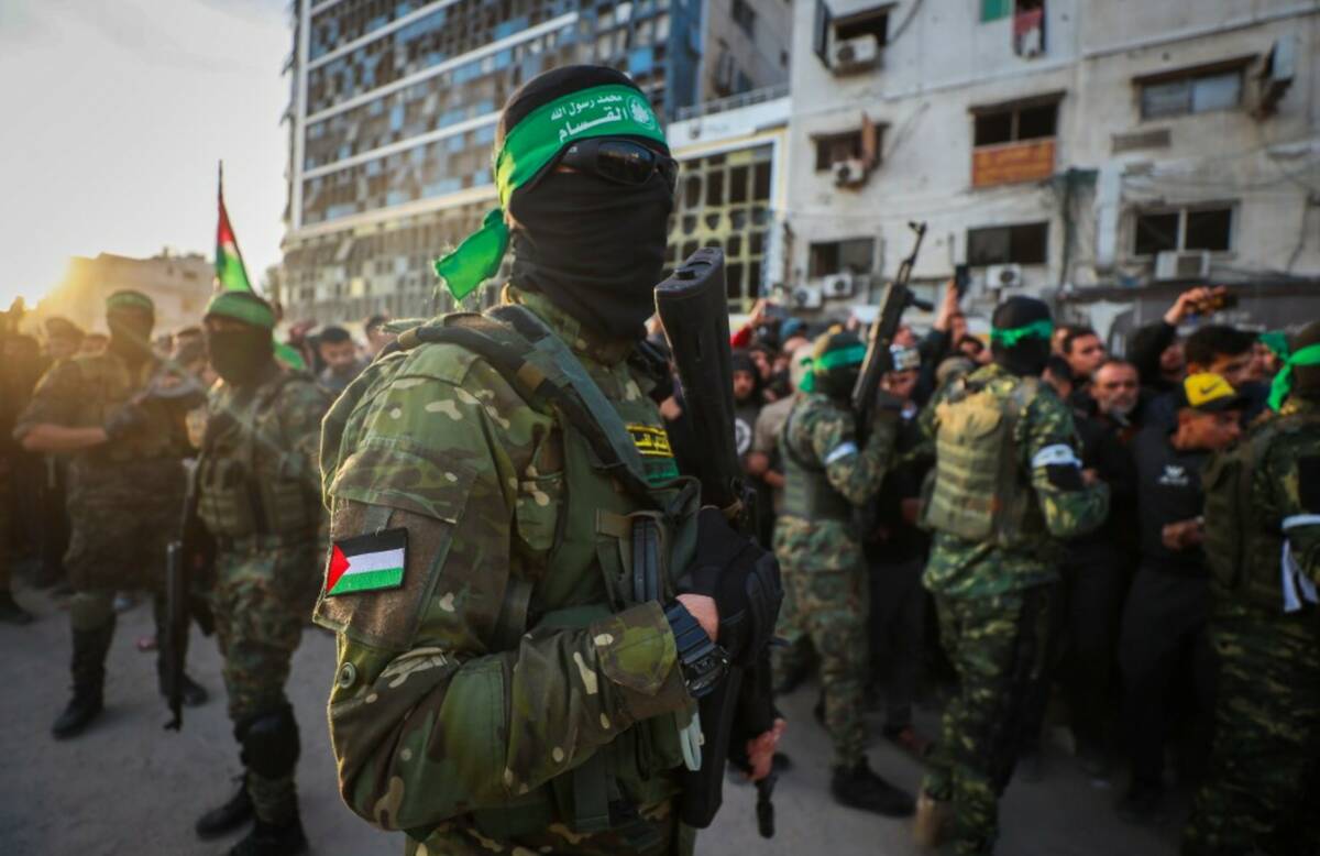 Fighters from the Qassam Brigades, the military wing of Hamas, control the crowd while Red Cros ...