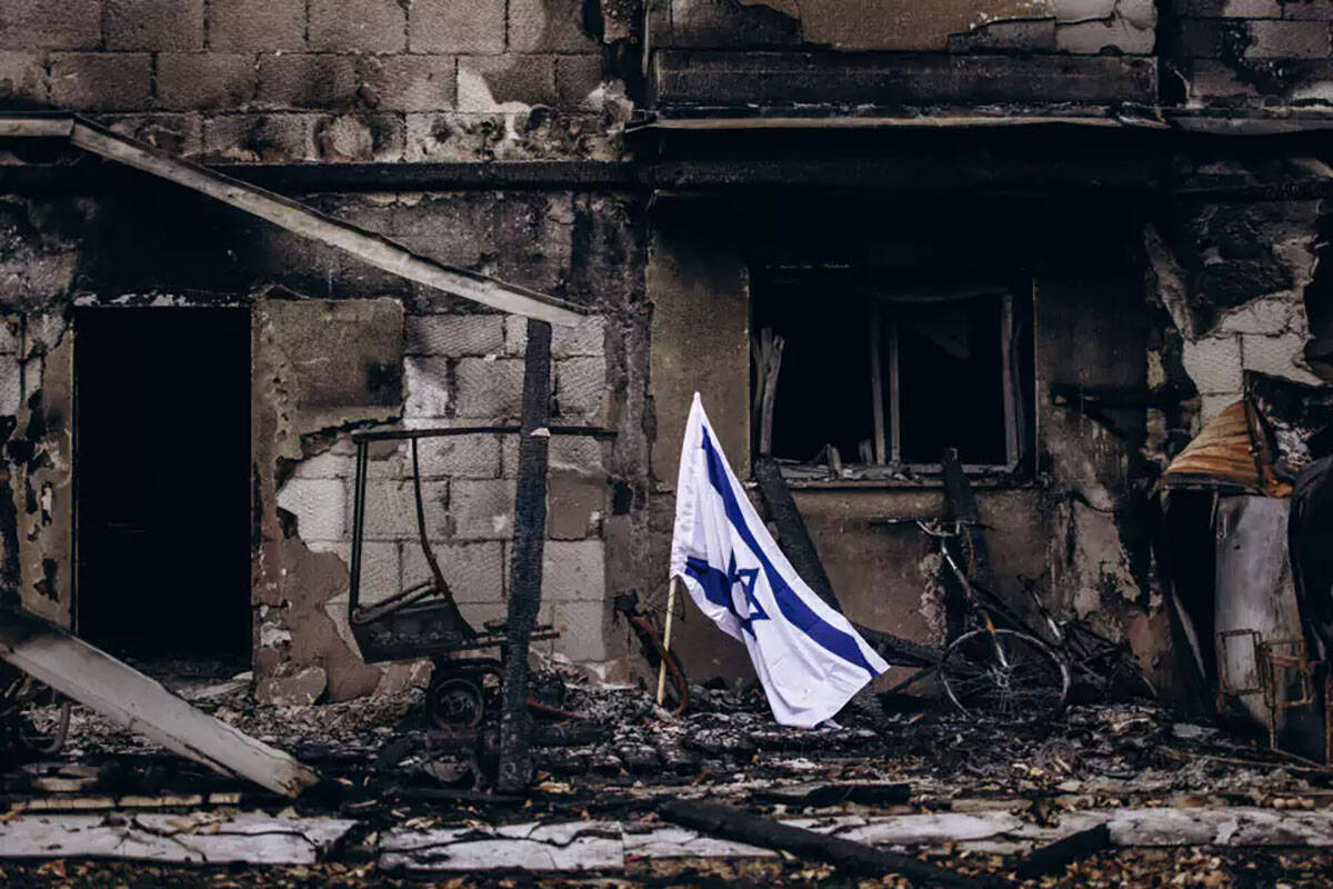 An Israeli flag flies beside a burned house in Kibbutz Be'eri. (Micha Brickman/Israel Hayom Arc ...