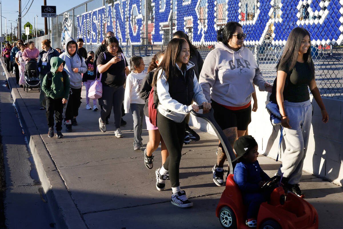 Parents and children walk on a sidewalk along Torrey Pines Drive as they participate in the ann ...
