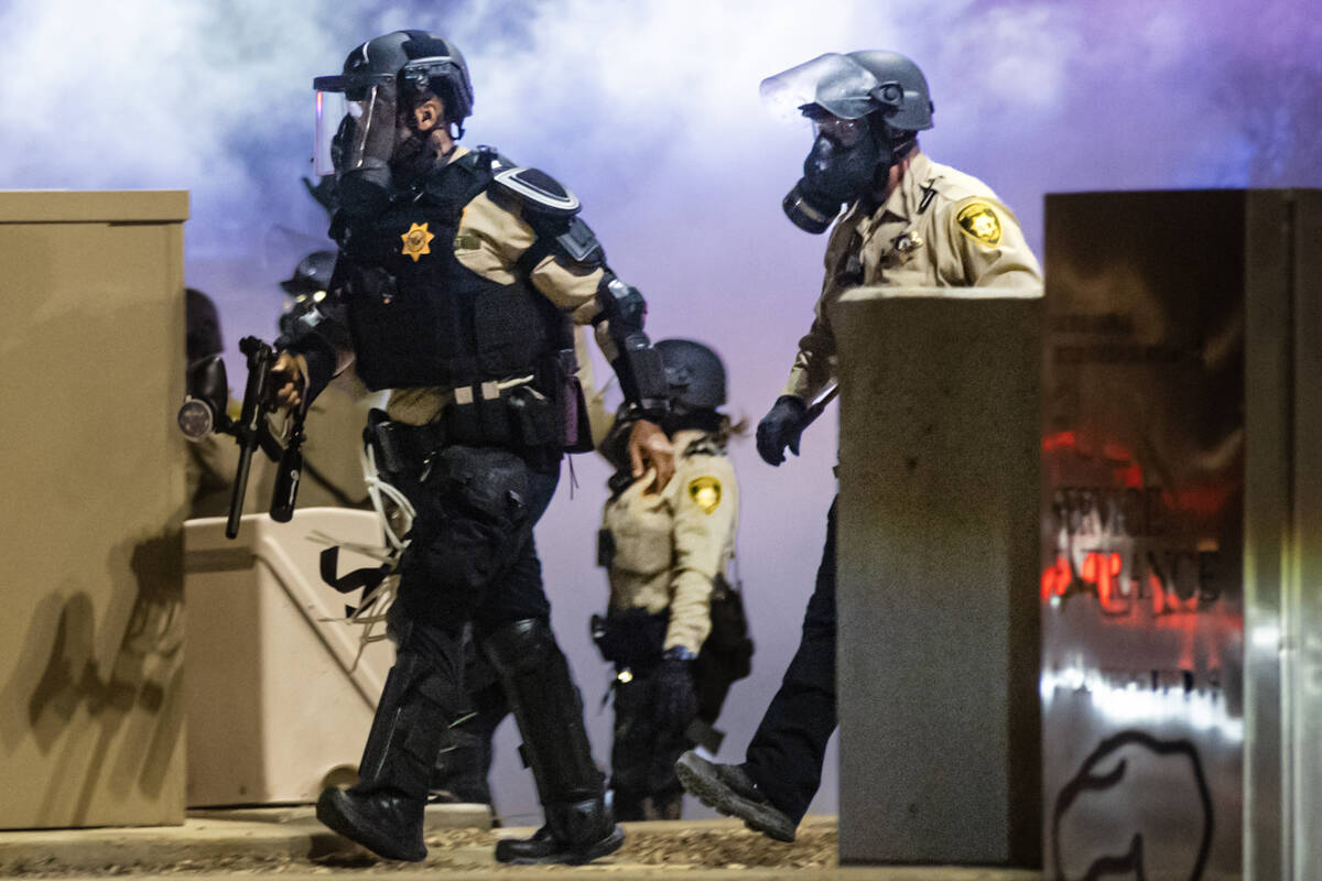 Las Vegas police advance with a pepper ball gun as teargas fills the air during a protest again ...