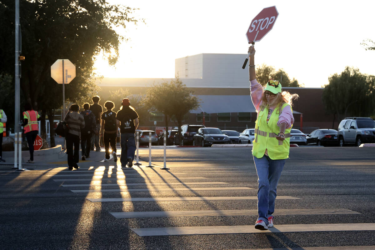 A paid crossing guard, who declined to give her name, stops traffic on North Buffalo Drive as s ...