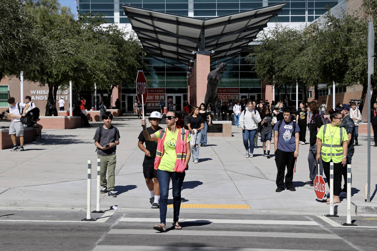 Bethany Limov, a volunteer with Walk Safely LV, helps students get across Whispering Sands Driv ...