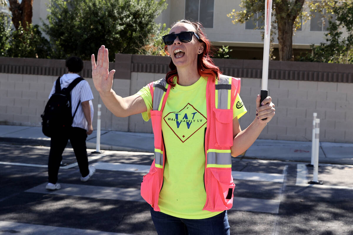 Bethany Limov, a volunteer with Walk Safely LV, helps students get across Whispering Sands Driv ...