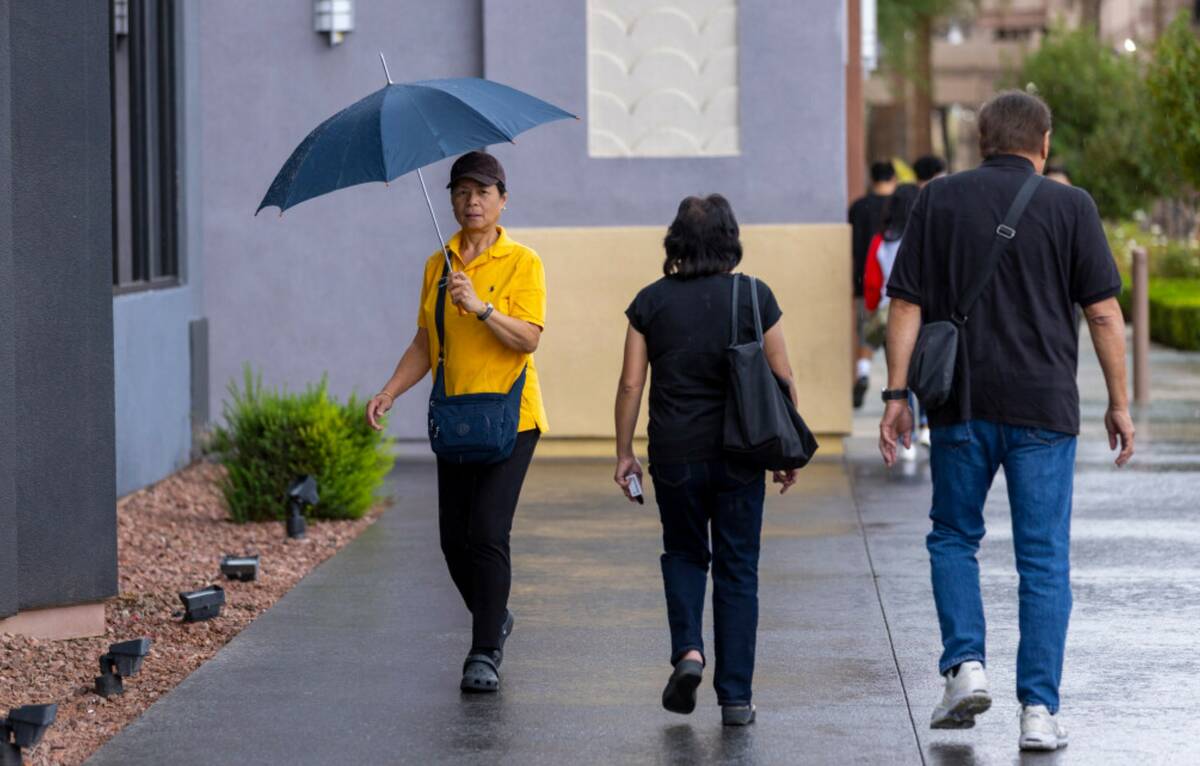 A woman keeps dry and the rain begins to fall about the Boulevard Mall as wet weather moves acr ...