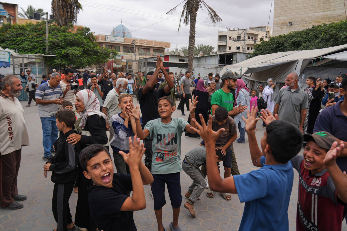 Palestinians celebrate following the announcement that Israel and Hamas have agreed to the firs ...