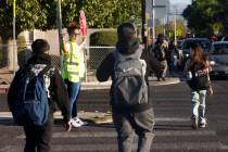 Students cross Owens Avenue with the assistance of Krista Holloway, a volunteer at Walk Safely ...