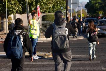 Students cross Owens Avenue with the assistance of Krista Holloway, a volunteer at Walk Safely ...