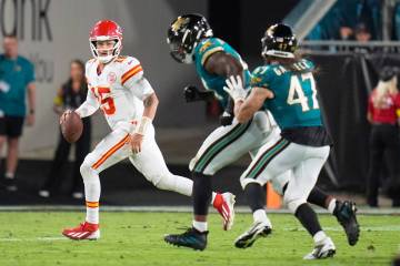 Kansas City Chiefs quarterback Patrick Mahomes, left, scrambles away from Jacksonville Jaguars ...