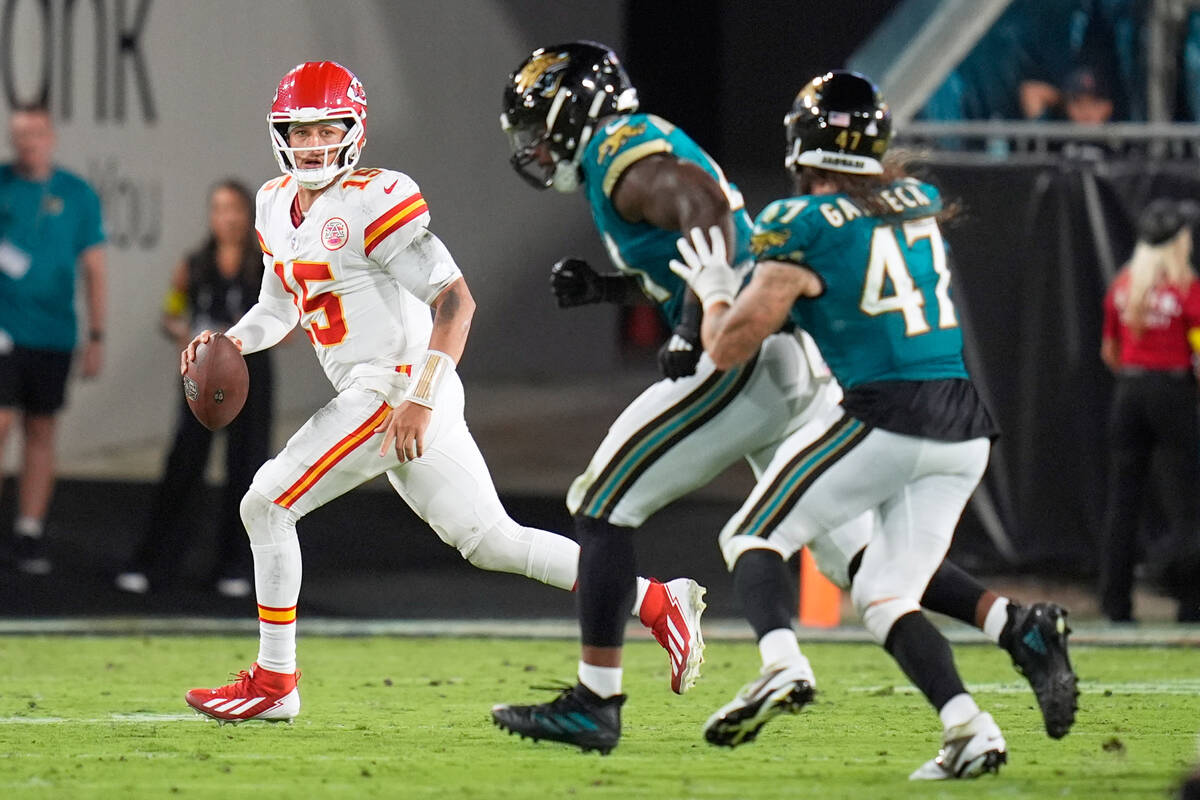 Kansas City Chiefs quarterback Patrick Mahomes, left, scrambles away from Jacksonville Jaguars ...