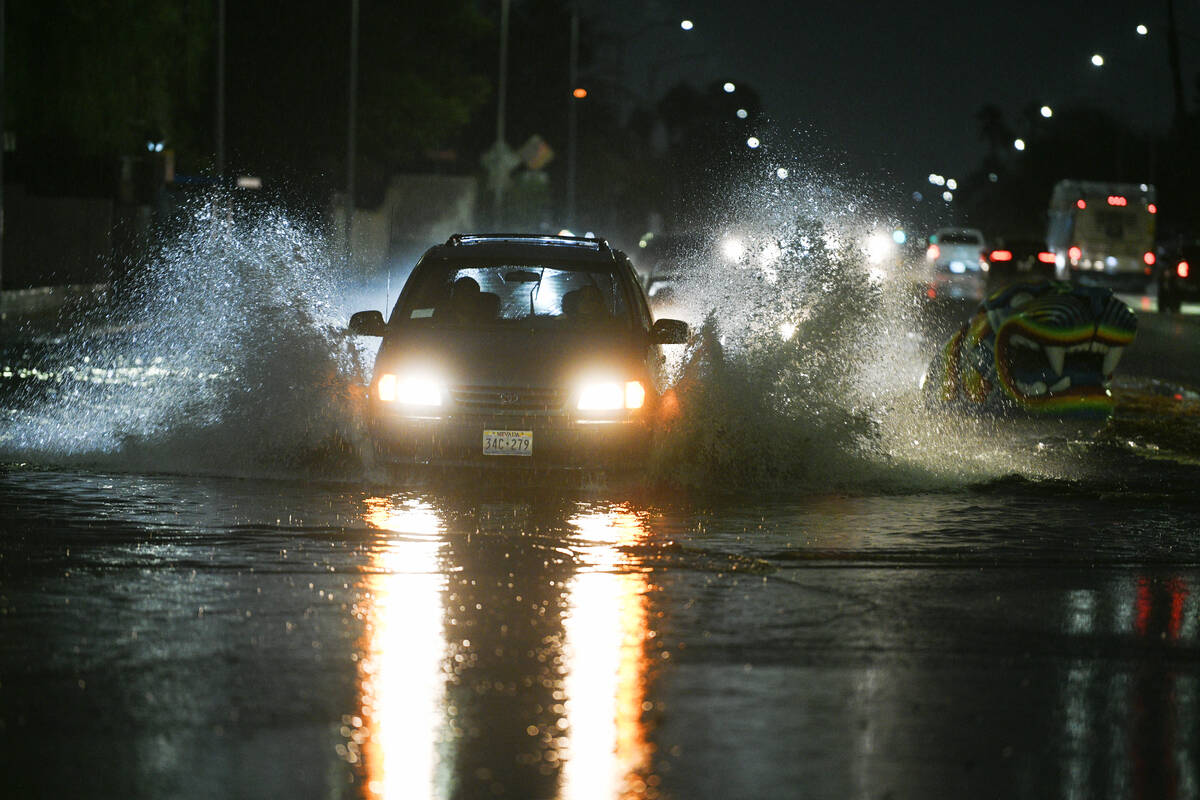 Cars travel through flood water on McLeod Drive near Desert Inn Road Friday, October 10, 2025, ...