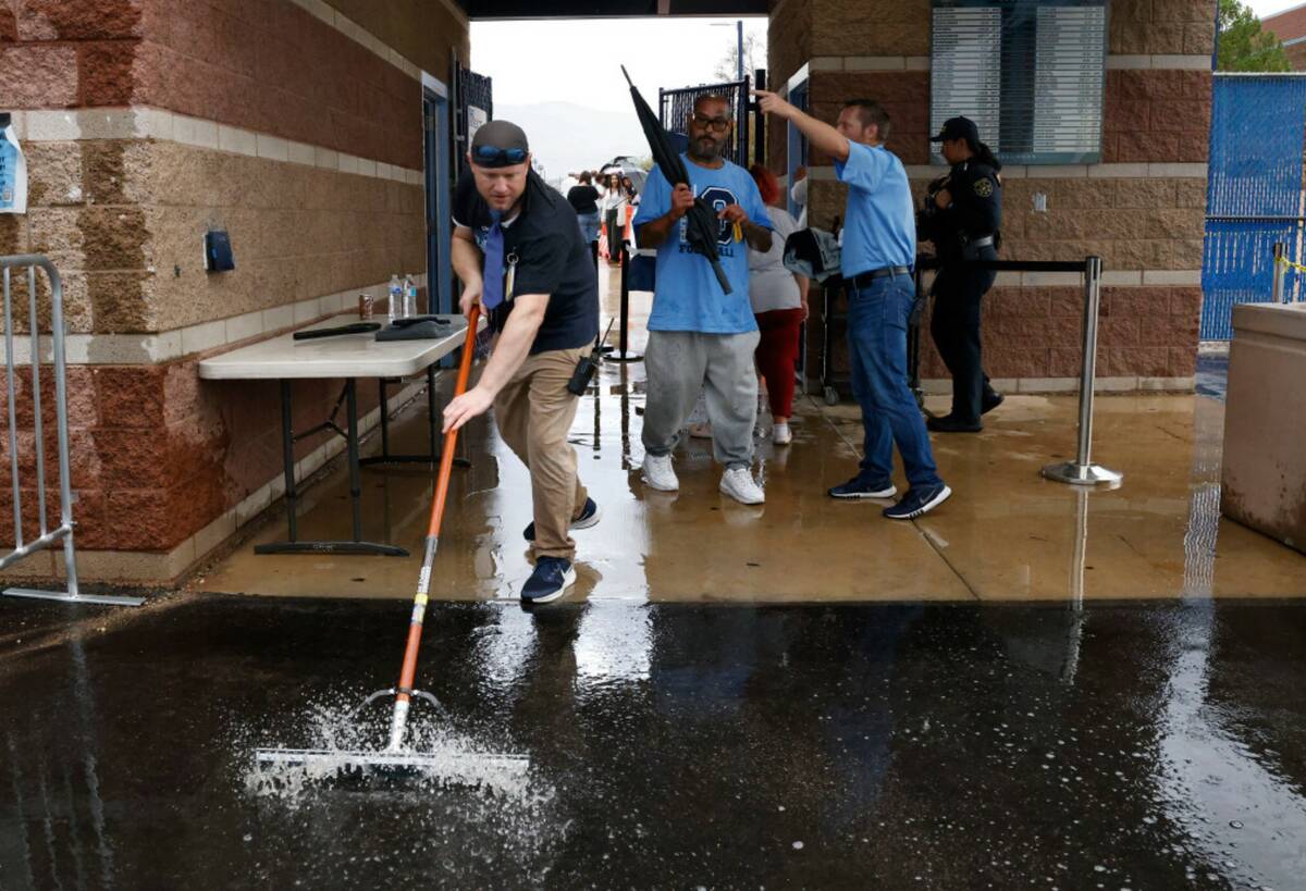 Centennial High School employee Michael Donnelly uses squeegee to remove water from a stadium e ...