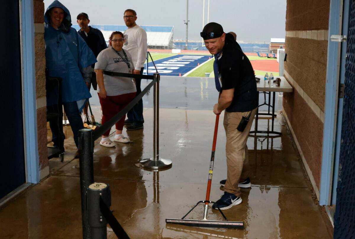 Centennial High School employee Michael Donnelly uses squeegee to remove water from a stadium e ...