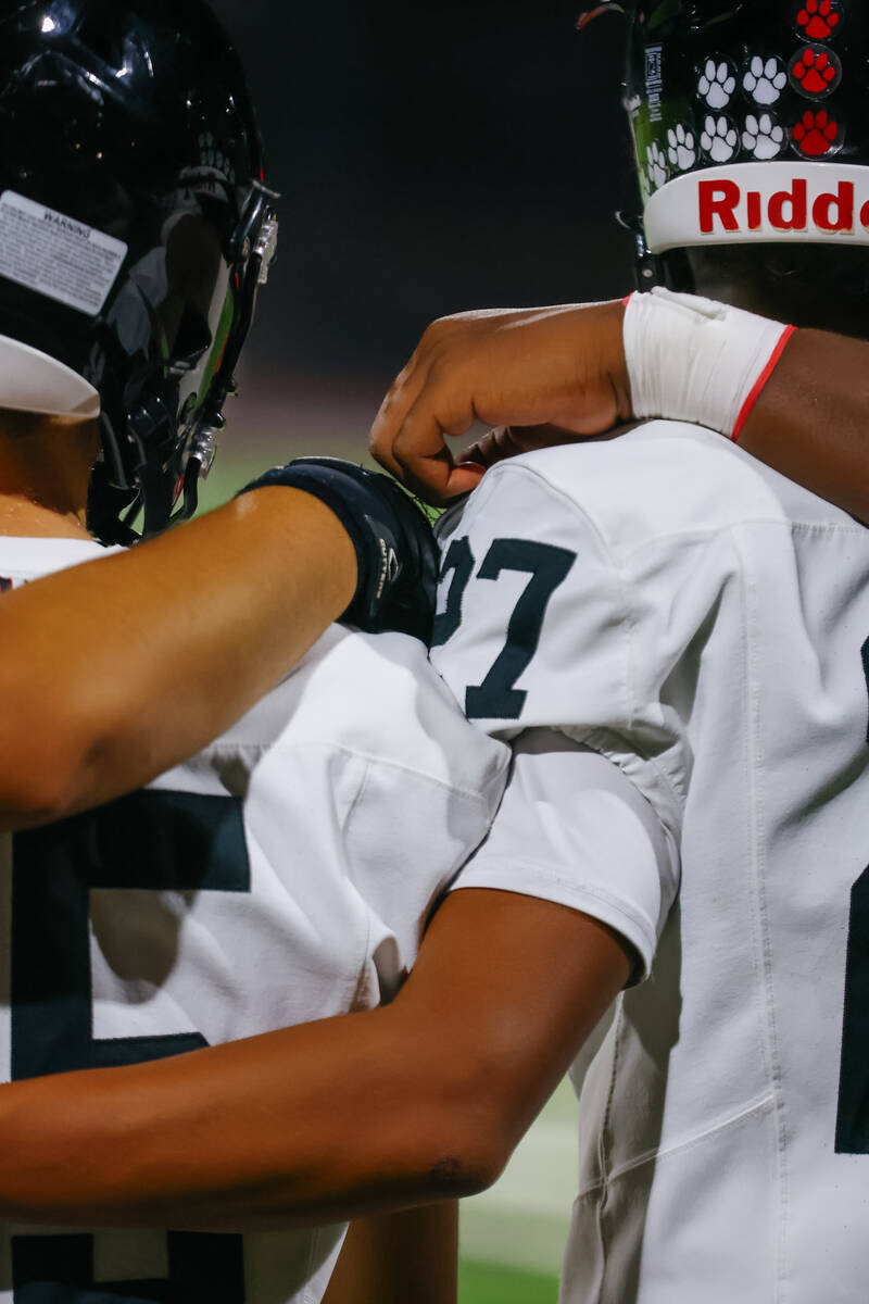Las Vegas players put their arms around each other as Desert Pines kicks off during a football ...