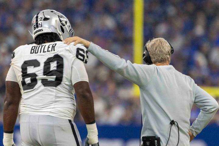 Raiders head coach Pete Carroll meets with Raiders defensive tackle Adam Butler (69) during a t ...