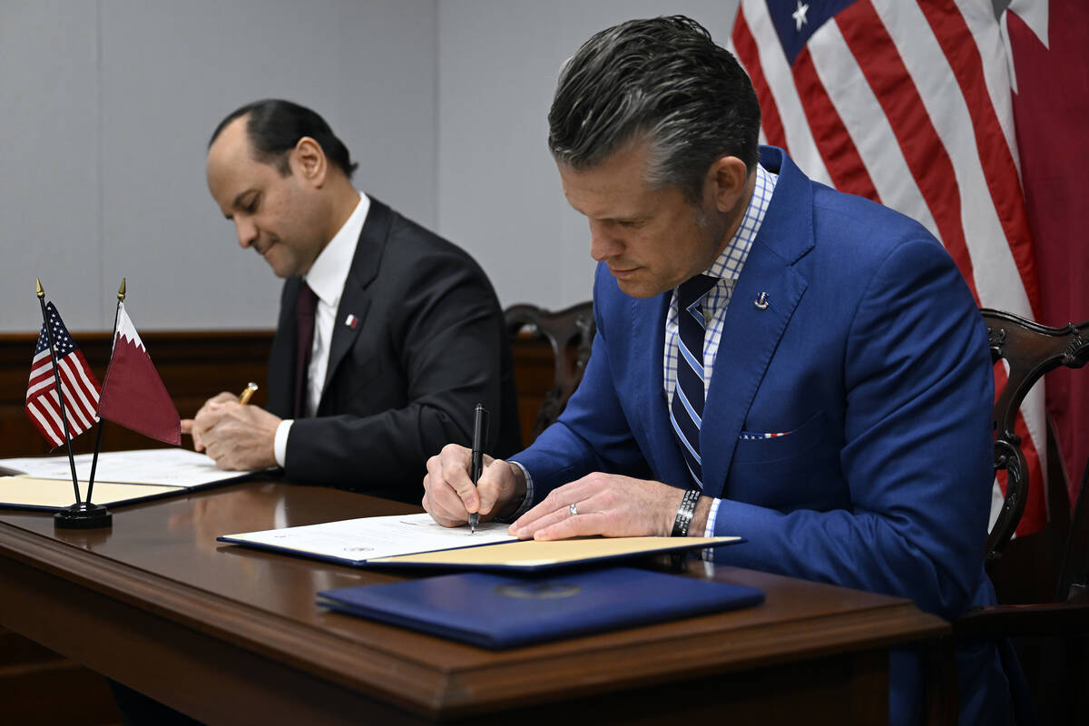 Qatari Defense Minister Sheikh Saoud Al Thani, left, signs an agreement with Secretary of War P ...