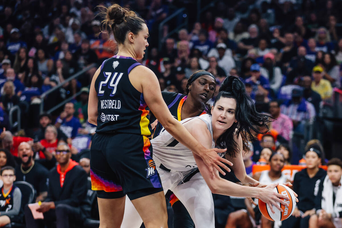 Aces center Megan Gustafson (17) passes the ball in between defense by Phoenix Mercury guard Ka ...