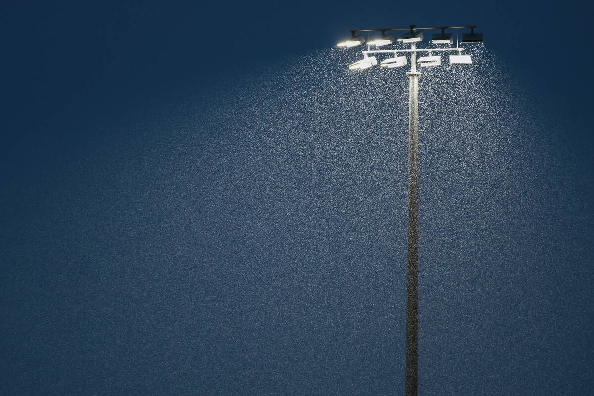Rain pours down under the stadium lights, where a football game between Desert Pines and Las Ve ...