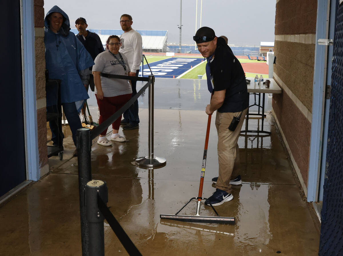 Centennial High School employee Michael Donnelly uses squeegee to remove water from a stadium e ...