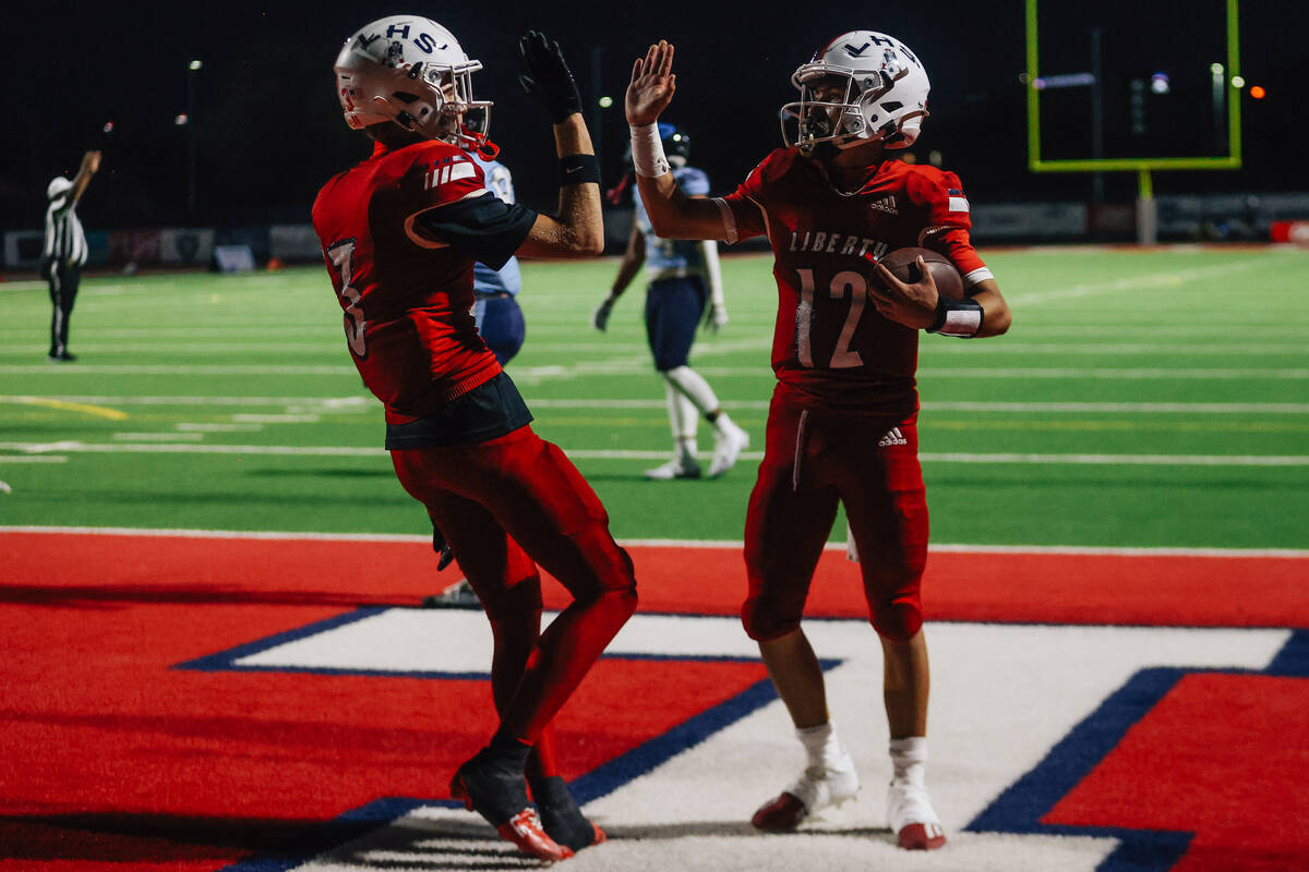 Liberty quarterback Selby Griego (12) high fives his teammate Brody Gavin after a touchdow ...