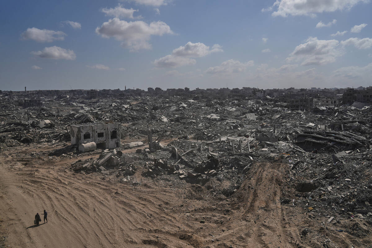 Two displaced Palestinians walk past destroyed buildings in the heavily damaged Sheikh Radwan n ...