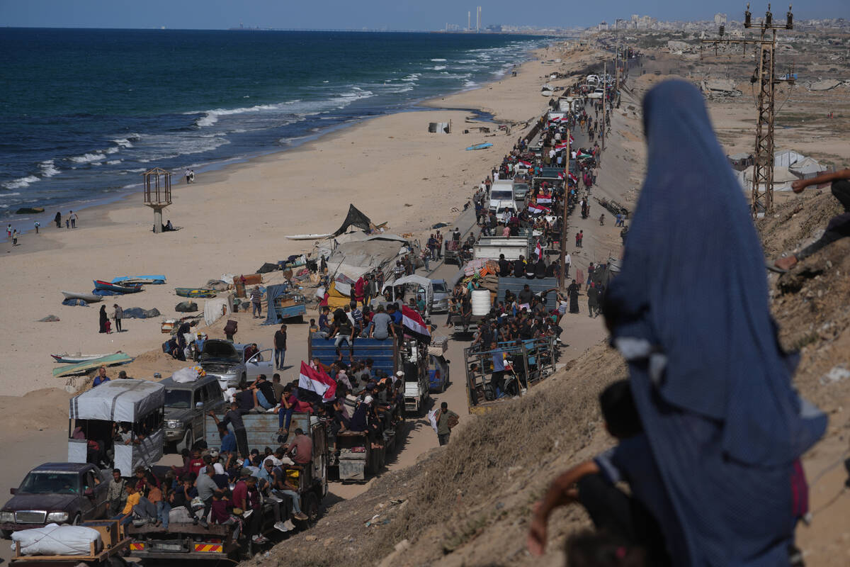 Displaced Palestinians ride on trucks loaded with belongings and wave Egyptian and Palestinian ...