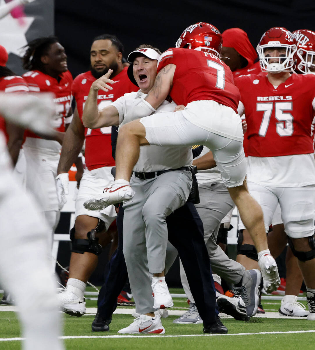 UNLV head coach Daniel Mullen celebrates his team 51-48 win with defensive back Jake Pope (7) d ...