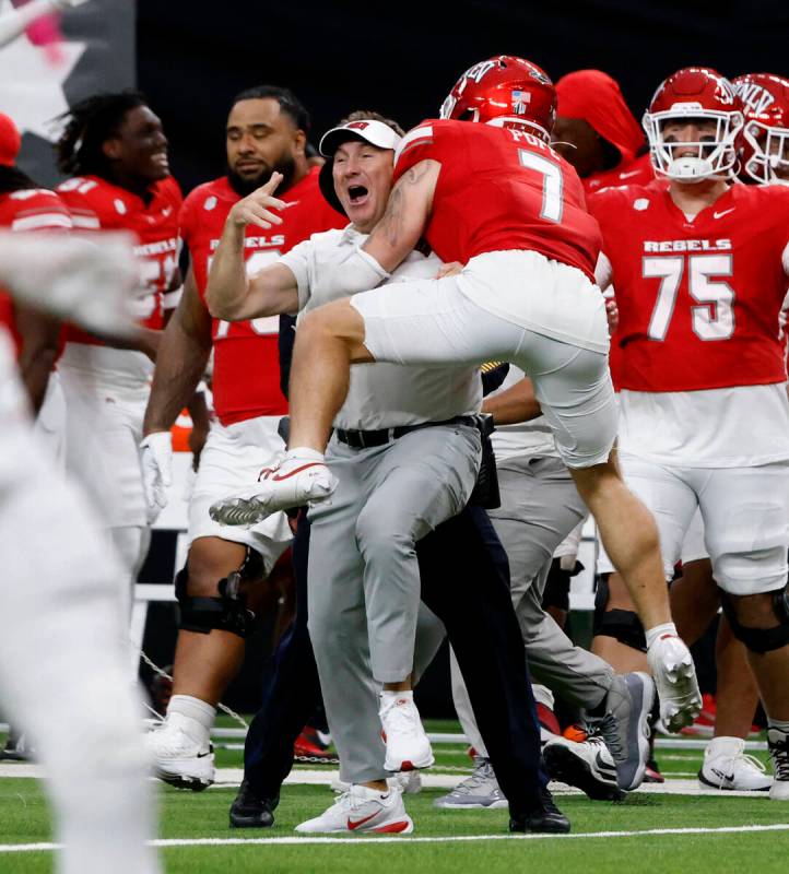 UNLV head coach Daniel Mullen celebrates his team 51-48 win with defensive back Jake Pope (7) d ...