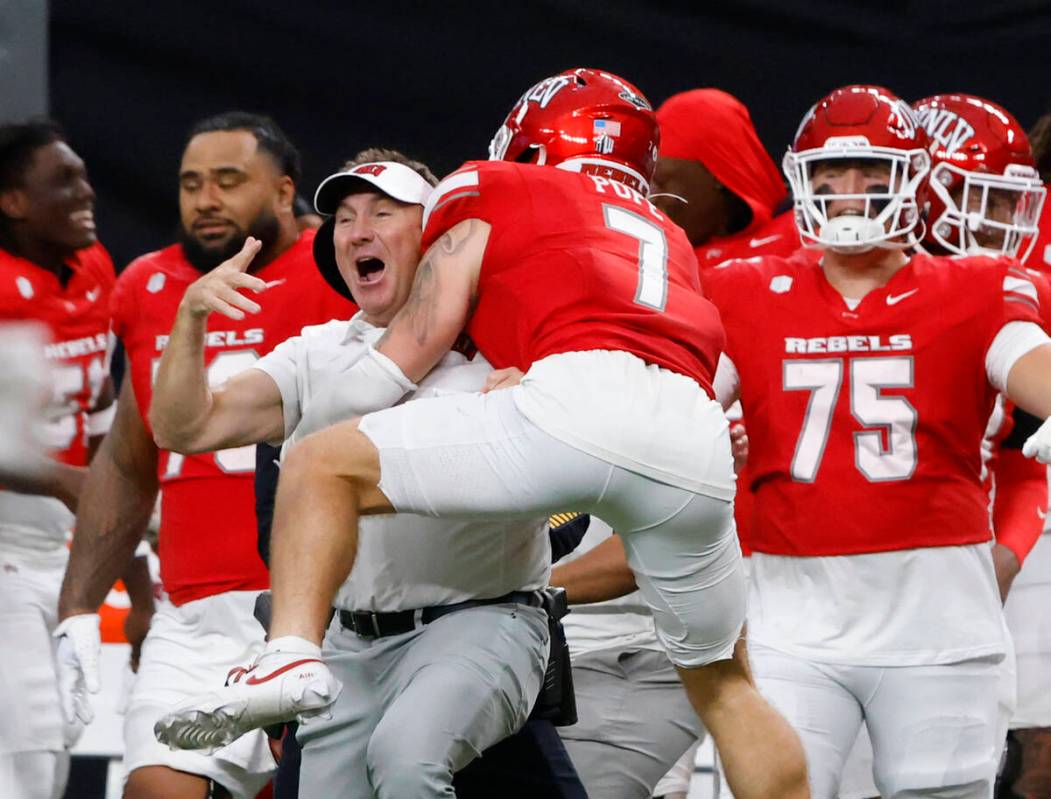 UNLV head coach Daniel Mullen celebrates his team 51-48 win with defensive back Jake Pope (7) d ...