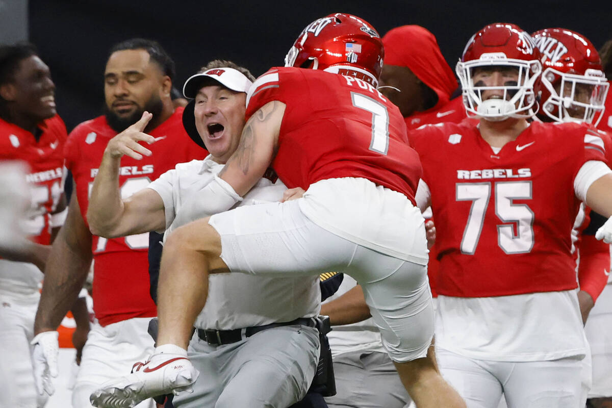 UNLV head coach Daniel Mullen celebrates his team 51-48 win with defensive back Jake Pope (7) d ...