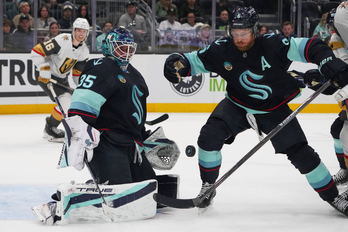 Seattle Kraken goaltender Joey Daccord, left, looks on as defenseman Adam Larsson (6) helps kee ...
