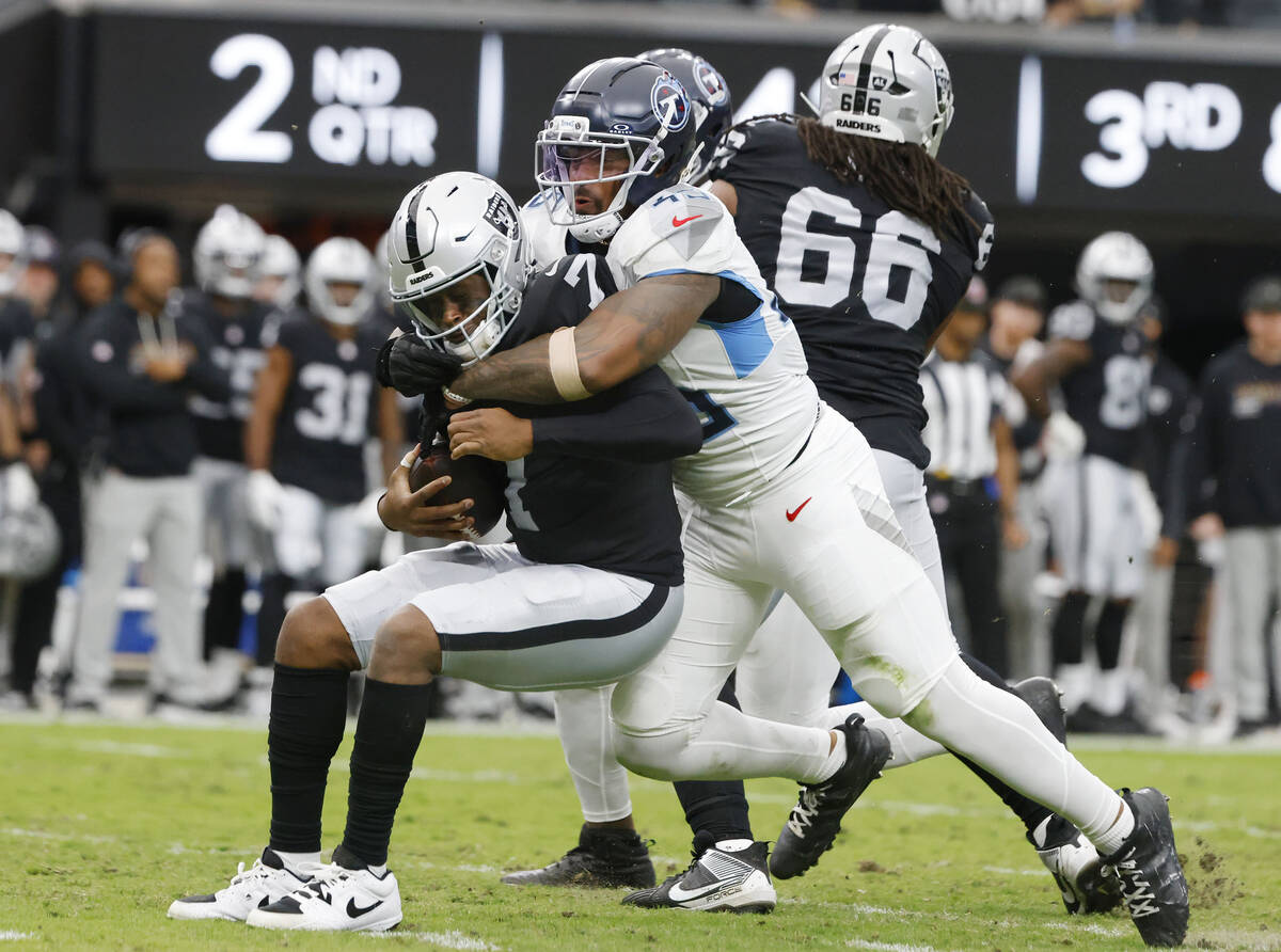Raiders quarterback Geno Smith (7) is sacked by Tennessee Titans linebacker Dre'Mont Jones ...