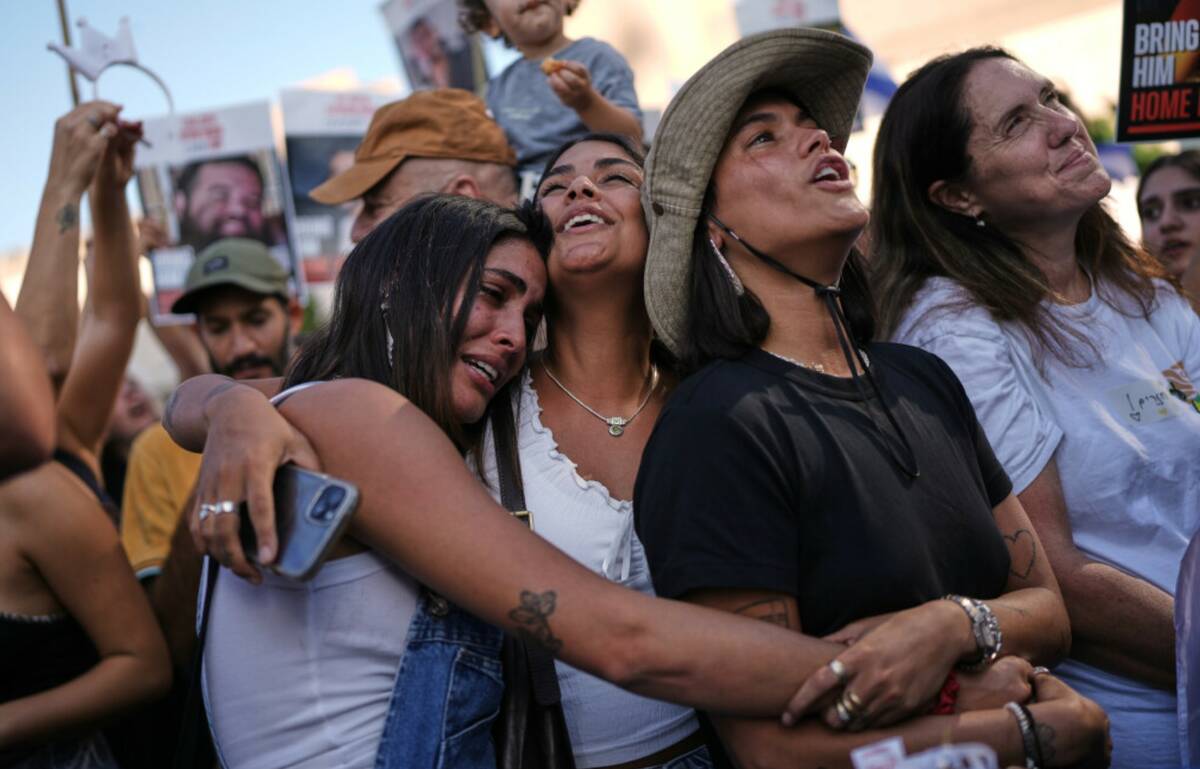 People react as they gather to watch a live broadcast of Israeli hostages released from Gaza at ...