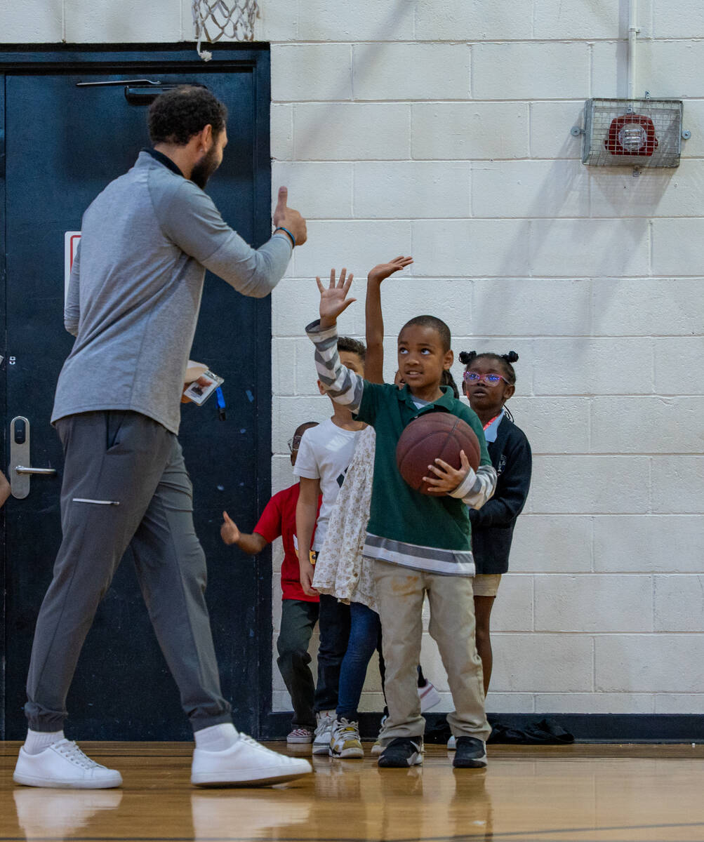 Former college basketball player Antanee Pinkard gives Ashton Ealy, 7, a thumbs-up inside the g ...