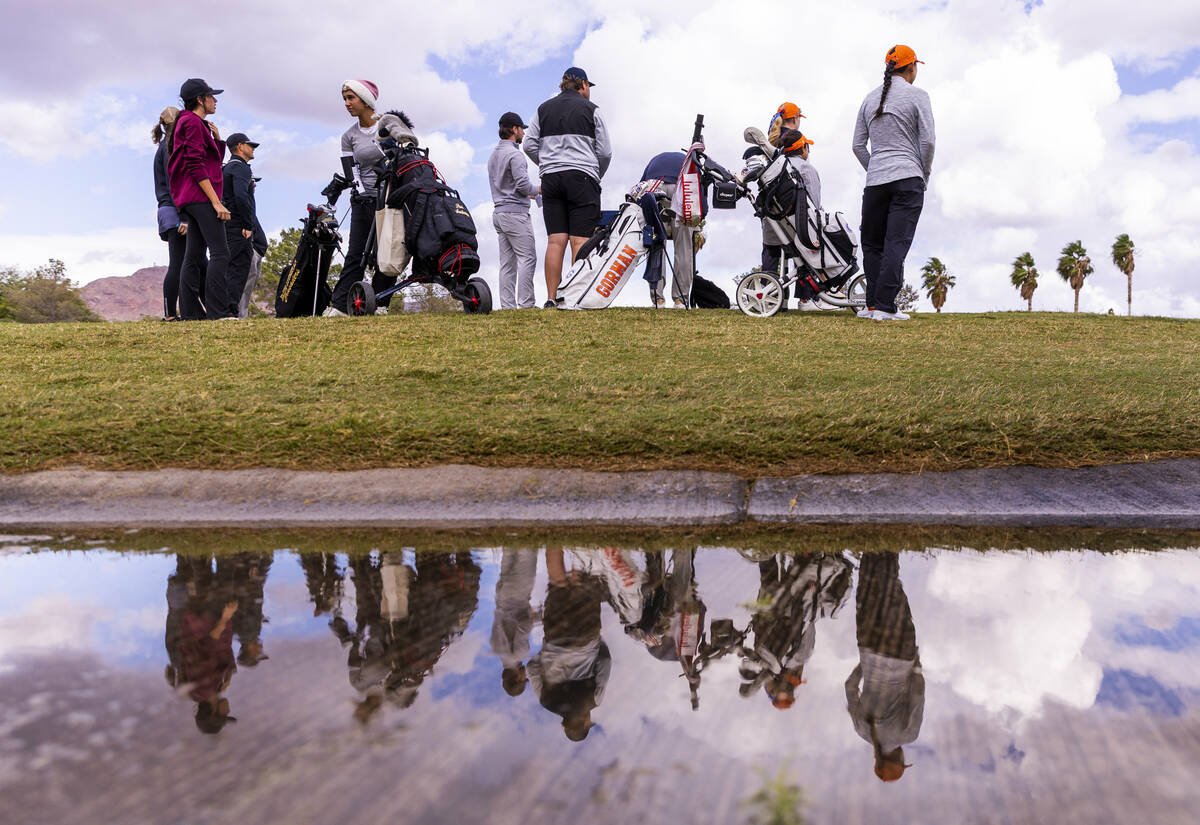 Participants are reflected in a puddle during the 5A girls golf state tournament at the Boulder ...