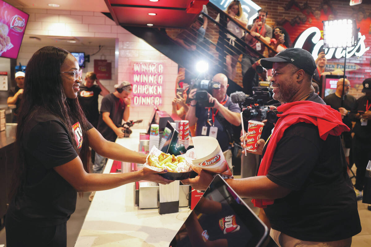Aces guard Jackie Young, left, serves Tim Fisher at Raising Cane’s on the Strip Tuesday, ...
