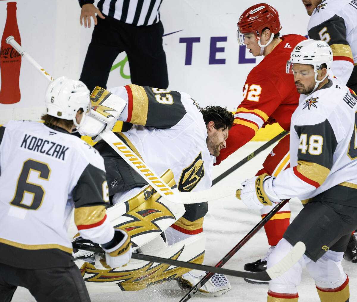 Vegas Golden Knights goalie Adin Hill, center, falls to the ice after losing his mask as Calgar ...