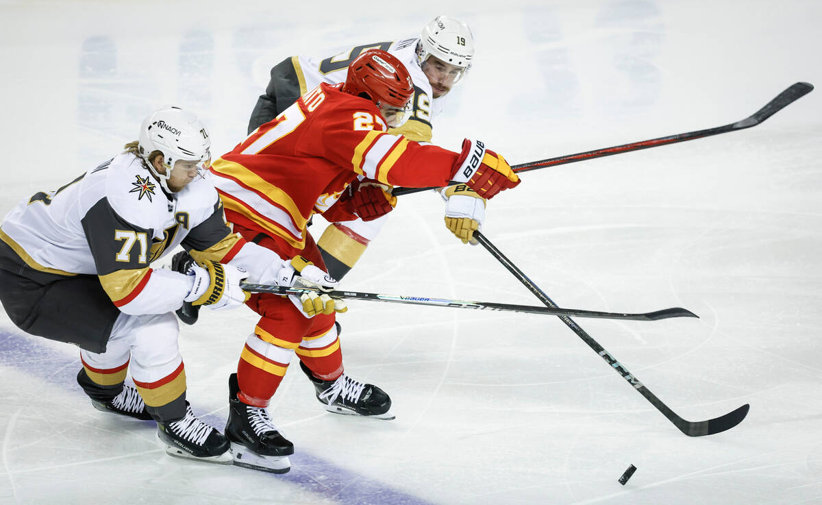 Vegas Golden Knights' William Karlsson, left, and Reilly Smith, right, check Calgary Flame ...