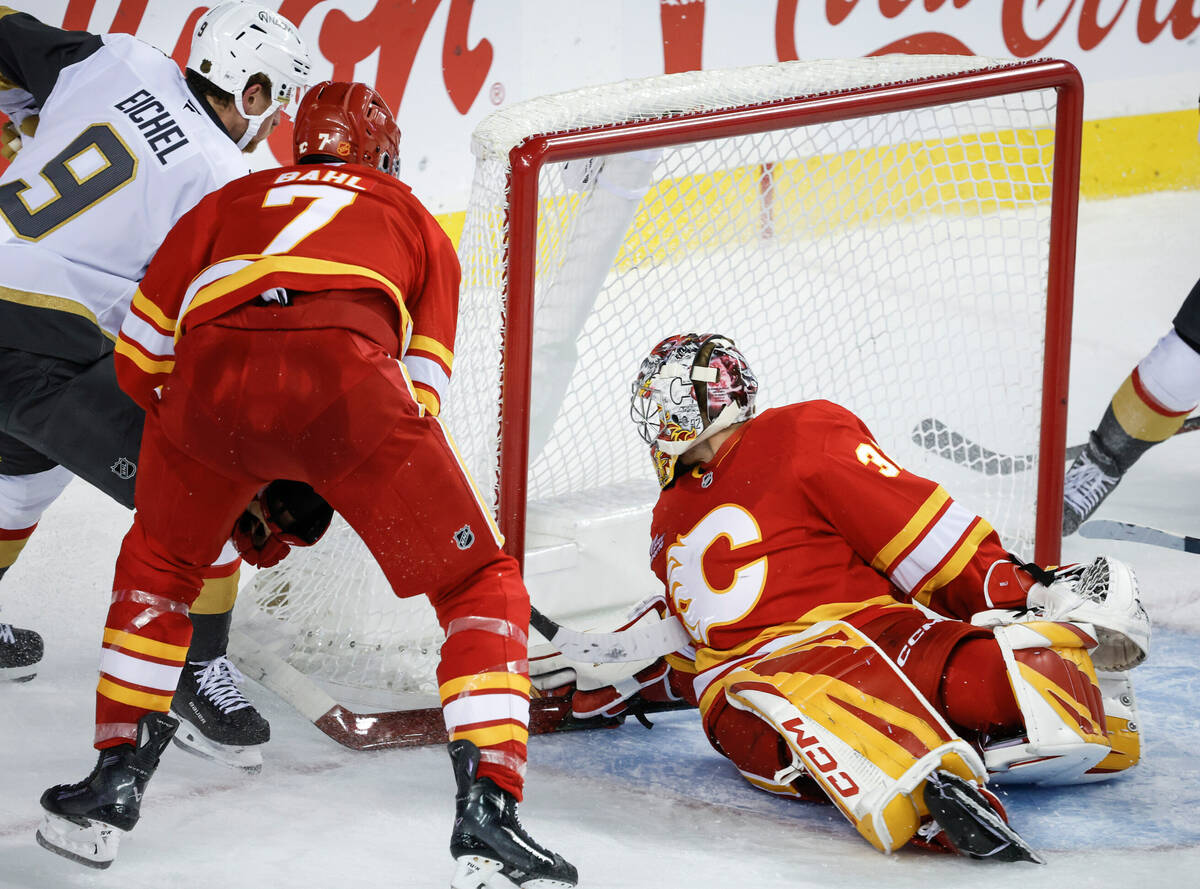 Vegas Golden Knights' Jack Eichel, left, scores on Calgary Flames goalie Dustin Wolf durin ...