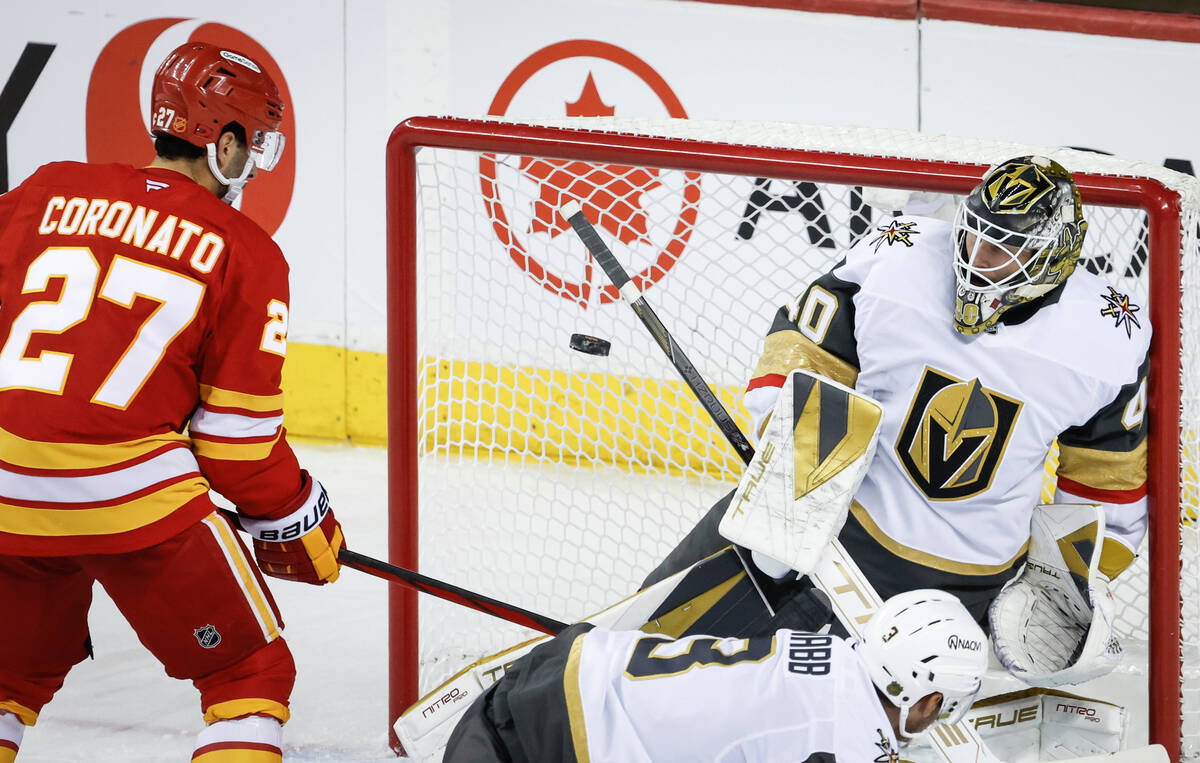 Vegas Golden Knights goalie Akira Schmid, right, stops a shot as Calgary Flames' Matt Coro ...