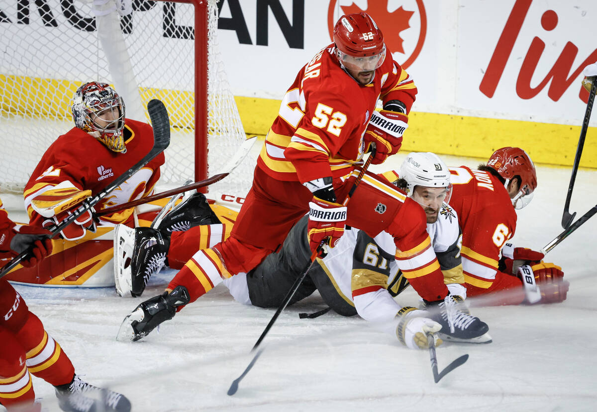 Vegas Golden Knights' Mark Stone, centre right, is checked by Calgary Flames' MacKenz ...