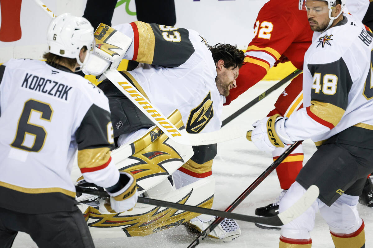Vegas Golden Knights goalie Adin Hill, center, falls to the ice after losing his mask as Calgar ...