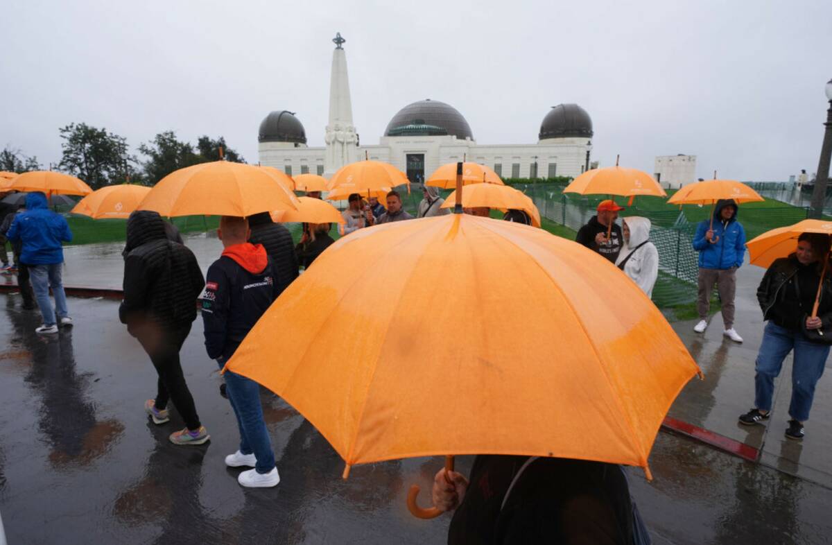 Tourists from Poland carry umbrellas as rain falls while visiting the Griffith Observatory Tues ...