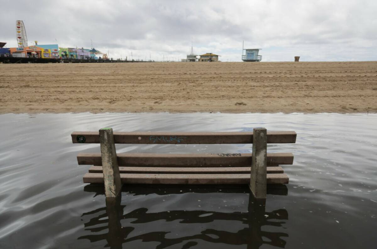 An empty bench sits in floodwaters in front of the Santa Monica Pier after heavy rains Tuesday, ...