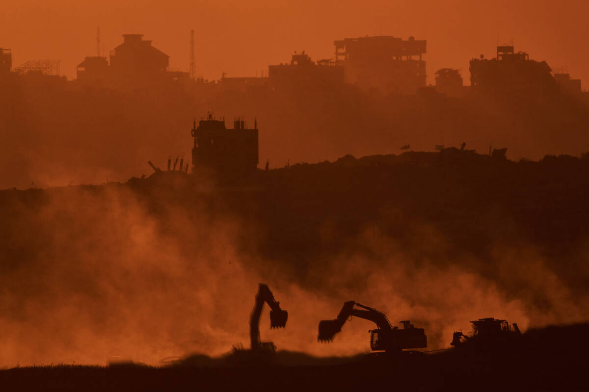 Israeli excavators work in the Gaza Strip as the sun sets, seen from southern Israel, Tuesday, ...