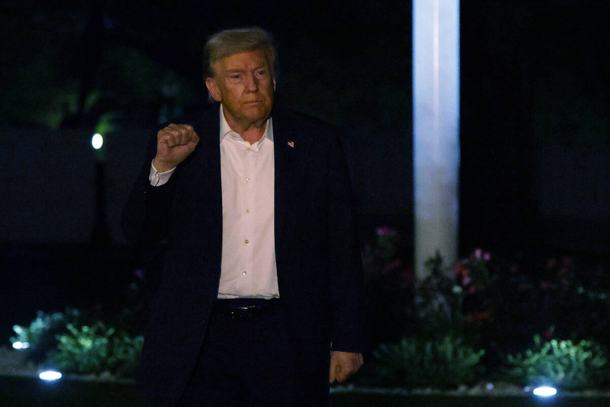 U.S. President Donald Trump holds up his fist as he walks on the South Lawn after he landed at ...