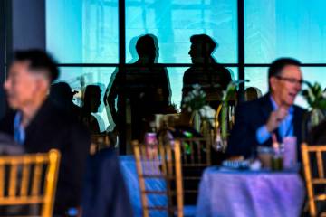 Invited guests are reflected in patio windows as they and others chat during the Vegas Tech Sum ...